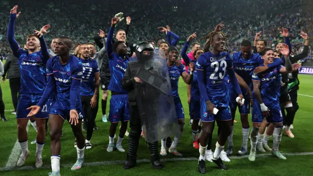 لاعبو نادي تشيلسي يحتفلون بجانب رجل أمن بعد الفوز ببطولة دوري المؤتمر الأوروبي لكرة القدم