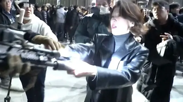 Žena rukama otima pušku policajcu