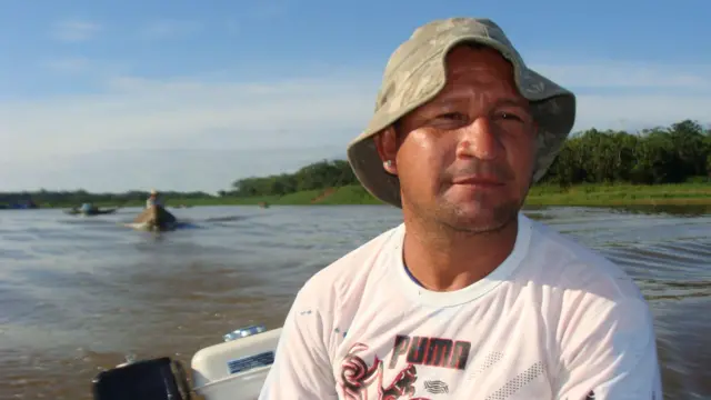 O manejador Pedro Canízio em um barco, com camiseta da maca Puma e um chapéu de pescador