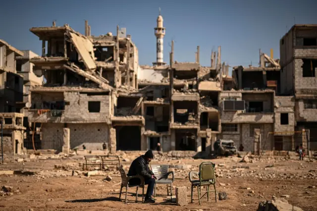 दमास्कसमध्ये उध्वस्त झालेल्या घरांसमोर पॅलेस्टिनी शरणार्थी 