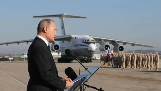 Владимир Путин на базе в Хмеймиме, на заднем плане - военный самолет и шеренга военных