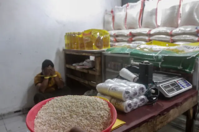 Seorang pria menutup wajah di pojokan di dalam warungnya.