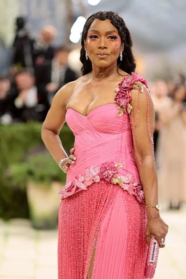 Angela Bassett tek omuz askılı pembe bir elbise giyiyor.
