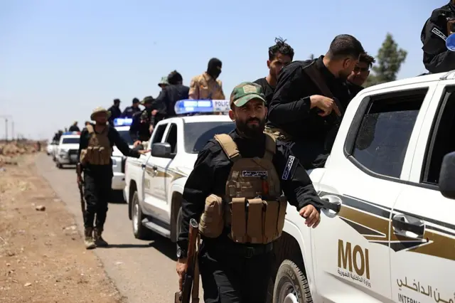 صورة تظهر صفاً من سيارات شرطة كتب عليها "وزارة الداخلية السورية"، ويقف بجوارها أفارد أمن مدججون بالأسلحة.