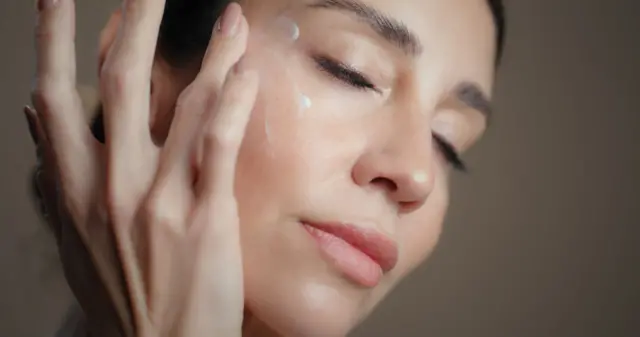 Mujer aplicándose crema en la cara
