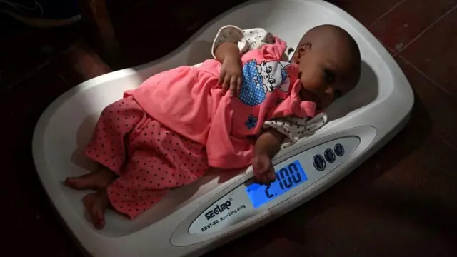 Bebê sendo pesado em uma balança em uma maternidade de Karachi, no Paquistão