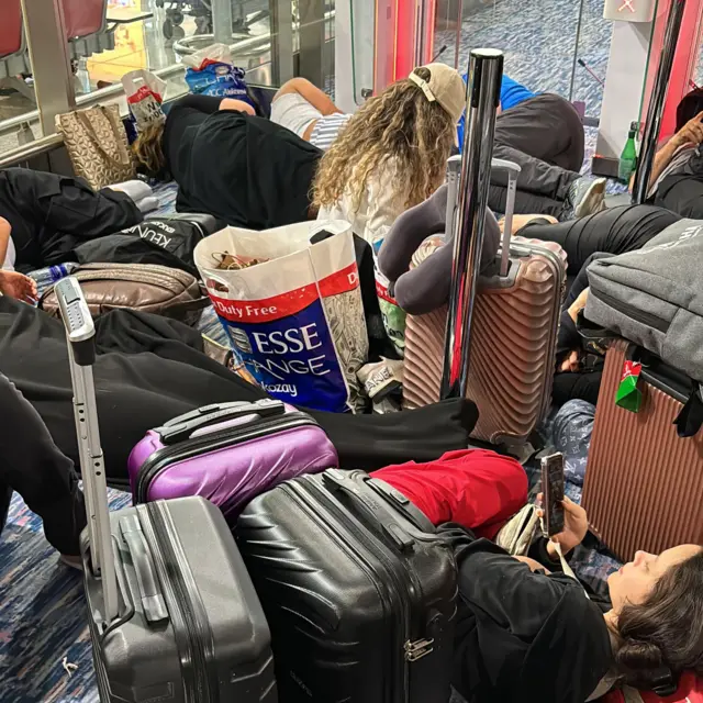 Malas e pessoas deitadas no carpete do aeroporto 