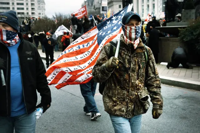 Apoiadornew betDonald Trump com jaqueta clamufada carrega bandeira dos EUA e veste máscara com bandeira dos EUA