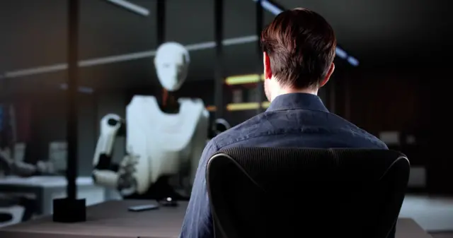 Un hombre de traje en una oficina conversando con un robot.