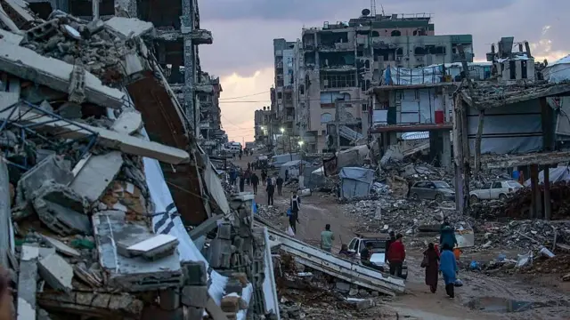 Personas desplazadas caminan entre edificios destruidos en Ciudad de Gaza en diciembre 2025.