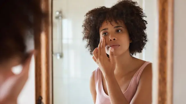 Mulher passando cosméticojackpotcity cassinofrente a um espelho