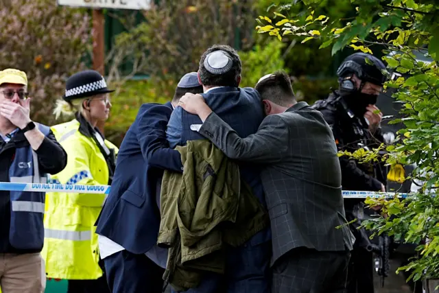 Membros da comunidade judaica confortam uns aos outros perto da Congregação Hebraica de Heaton Park em Crumsall, Manchester