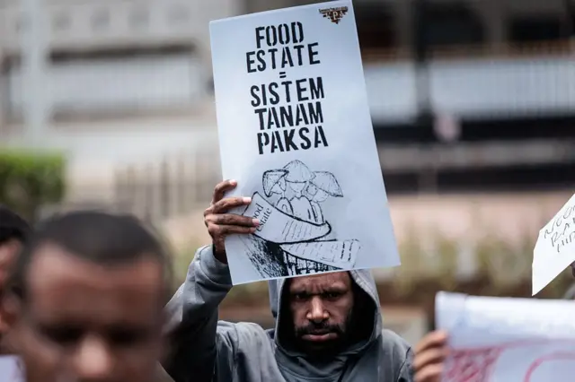 Para pengunjuk rasa memegang spanduk bertuliskan "Kawasan Pangan = Sistem Tanam Paksa (Sistem Pertanian Paksa)" saat berunjuk rasa menentang rencana pemerintah untuk melepaskan kawasan hutan di Papua Selatan untuk proyek-proyek strategis nasional di bidang pangan, energi, dan pertahanan, di depan kantor Badan Agraria dan Tata Ruang/Badan Pertanahan Nasional (ATR/BPN) di Jakarta, pada 7 Oktober 2025. 