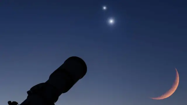 A camera lens is pointed at a crescent Moon and two bright bodies in the night sky