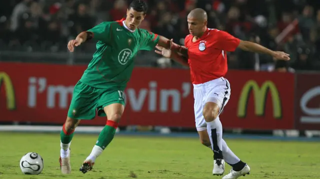 Marouane Chamakh, en tenue verte du Maroc, protège le ballon d'un joueur égyptien.