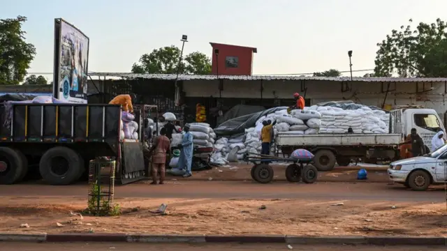 Workers dey unload bags of rice and flour from vehicle
