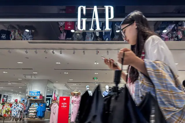 Joven pasa por delante de una tienda de Gap en Chongqing, China.
