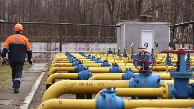 Робітник проходить біля газових труб з вентилями