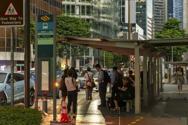 Para penumpang di halte bus pada malam hari di Singapura, Selasa, 14 Mei 2024.