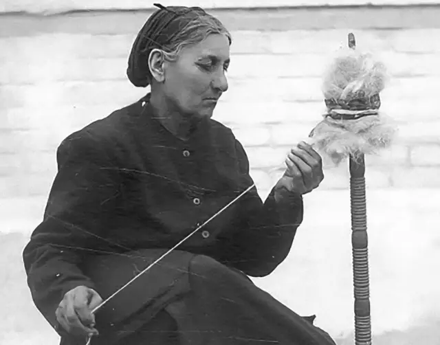 Старе чорнобіле фото жінки, яке пряде нитку 