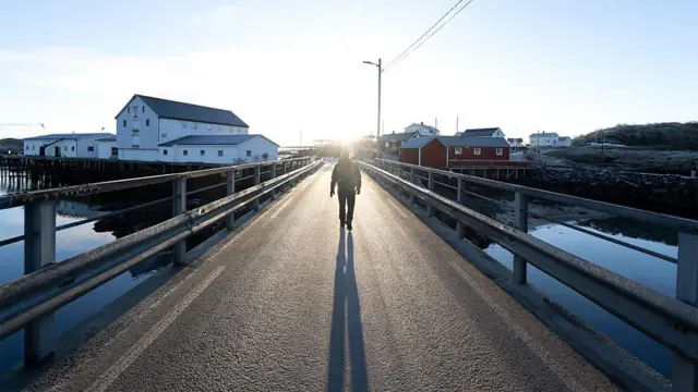 አመሻሽ ላይ በድልድይ ላይ የሚራመድ ሰው