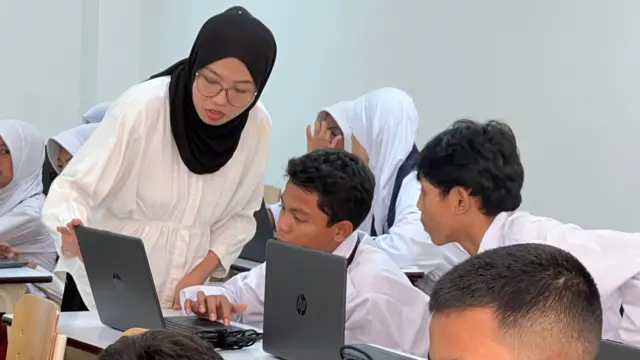 Seorang guru di Sekolah Rakyat yang berada di Sentra Handayani, Jakarta sedang memandu seorang siswa menggunakan learning management system