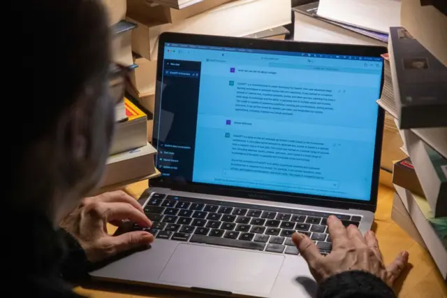 Un hombre trabaja en una laptop con un chatbot