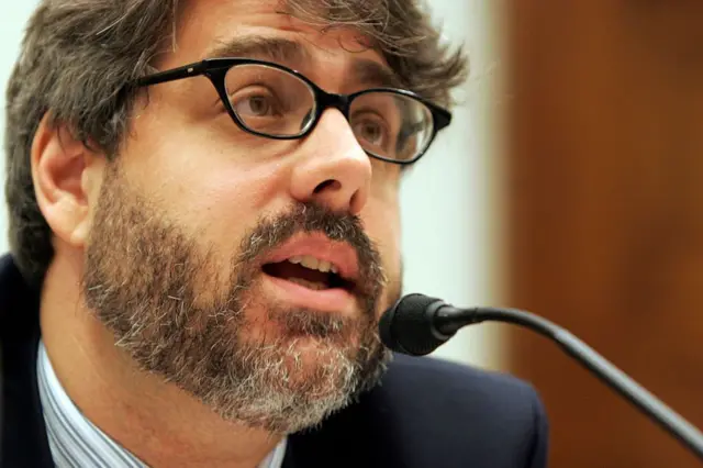 El abogado y activista Daniel Kovalik, con gafas y barba, delante de un micrófono