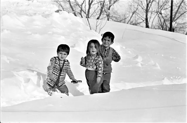 Karda oynayan üç küçük çocuk 