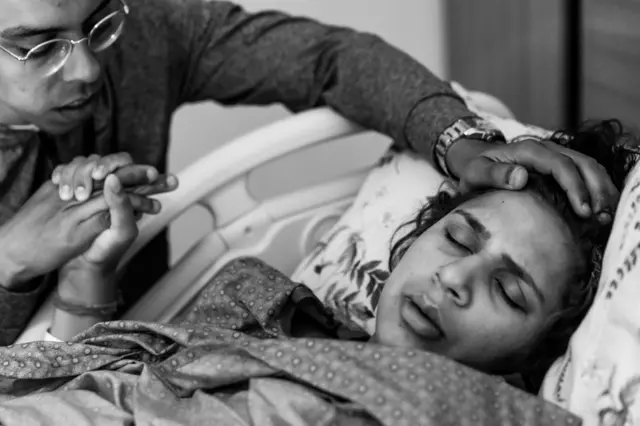  
Exhausted mother closes eyes during labor while husband soothes her