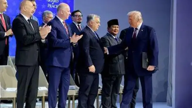 Дональд Трамп на сцені вітається за руку з іншими підписантами статуту Ради миру.