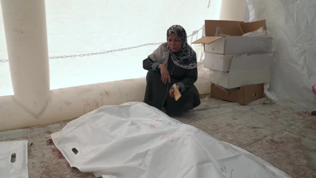 سيدة تجلس بجوار جثث بعض أقاربها الذين سقطوا خلال القصف الإسرائيلي.