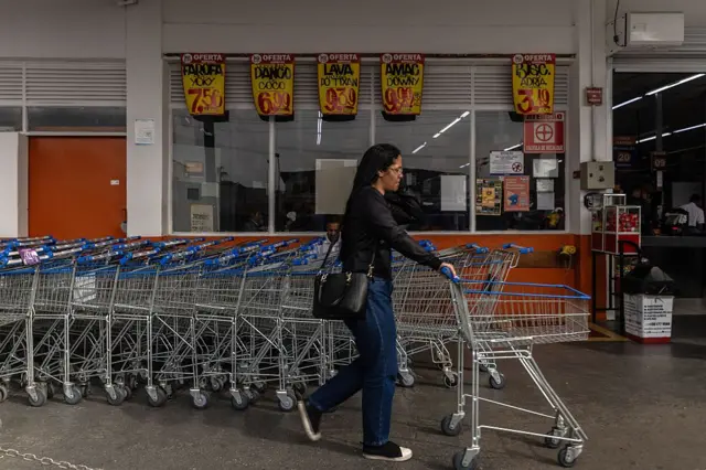 Um cliente empurra um carrinho em um supermercado.