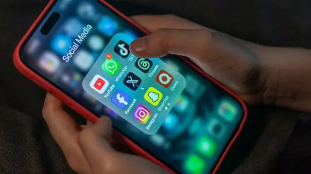 Seorang anak laki-laki berusia 12 tahun melihat layar iPhone yang menampilkan berbagai aplikasi media sosial termasuk TikTok, Facebook dan X.