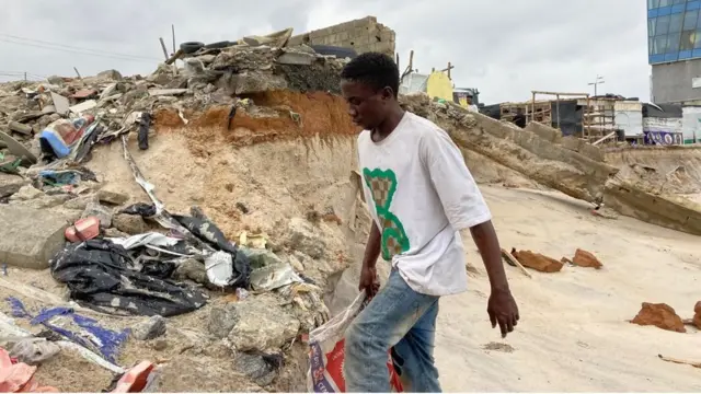 A young man walks among the rubbles on the beach