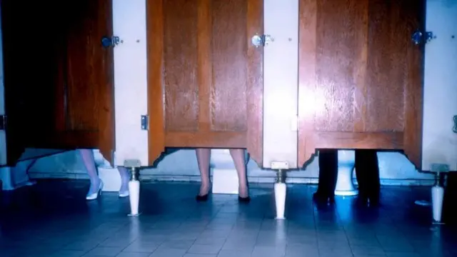 ਜਨਤਕ ਪਖਾਨਿਆਂ ਦੇ ਵੱਖ ਵੱਖ ਸਟਾਲ ਵਿੱਚੋਂ ਦਿਸਦੀਆਂ ਵੱਖ ਵੱਖ ਵਿਅਕਤੀਆਂ ਦੀਆਂ  ਲੱਤਾਂ 