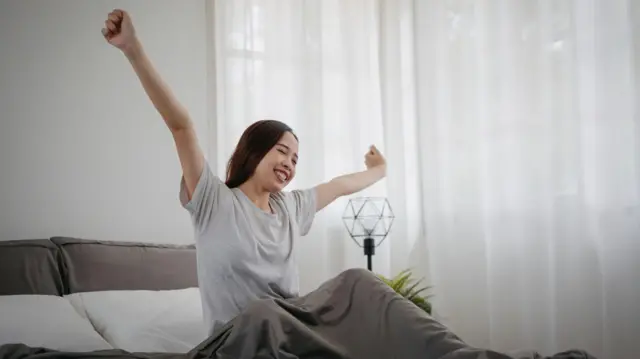 Seorang perempuan berbaring di tempat tidur di kamarnya sendiri.