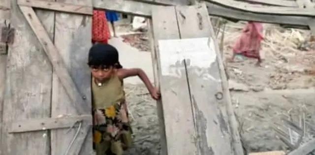 A Bangladeshi cyclone-affected girl dey frame with her destroyed house door