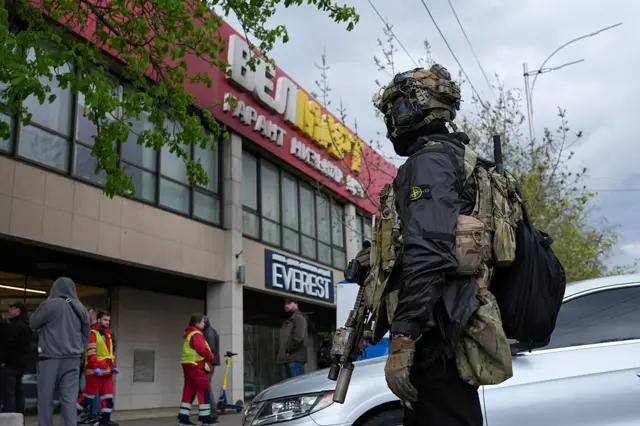 Боєць спецпідрозділу зі броєю стоїть біля магазину 