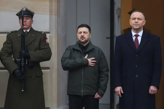 Prezydenci Polski i Ukrainy, Karol Nawrocki i Wołodymyr Zełenski, słuchają hymnu podczas ceremonii powitalnej na dziedzińcu Pałacu Prezydenckiego w Warszawie. 19 grudnia 2025 r. 