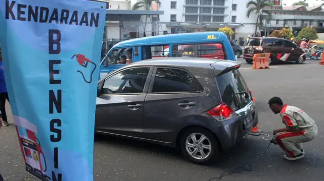 Petugas mengukur emisi gas buang sebuah kendaraan roda empat di jalan Trunojoyo, Malang, Jawa Timur, Rabu (26/7/2023).