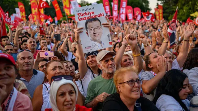 1 Temmuz 2025'te İstanbul Saraçhane'de, İmamoğlu'nun tutukluluğunun 100. gününde düzenlenen eyleme katılan kalabalıklar. Bir kişi, Ekrem İmamoğlu'nun üzerinde olduğu bir döviz taşıyor. 