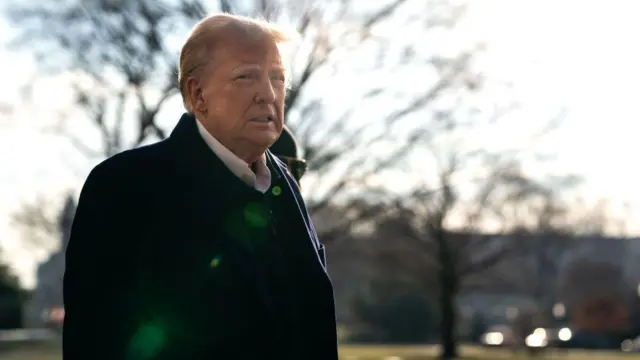 Donald Trump mặc áo khoác tối màu và áo sơ mi trắng, phát biểu với các phóng viên khi ông và Đệ nhất phu nhân Melania Trump chuẩn bị rời Nhà Trắng trên trực thăng Marine One vào ngày 24 tháng 1 năm 2025 tại Washington, DC.
