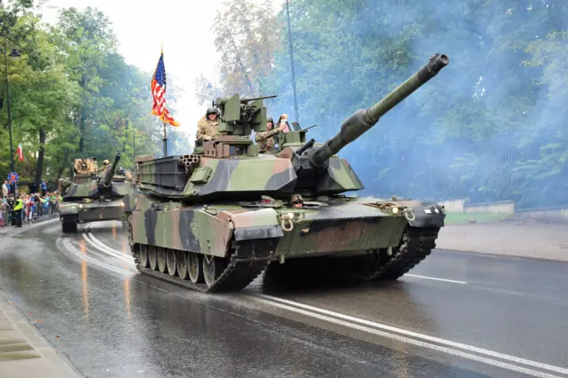 Des chars Abrams américains défilent lors de la Journée des forces armées polonaises à Varsovie en Pologne, en 2016. La foule observe le défilé depuis le bord de la route.
