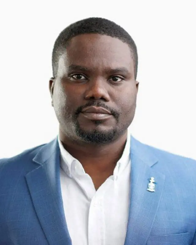 Porofeseri Guy Bucumi yambaye ikoti y'ubururu hamwe n'ishati yera