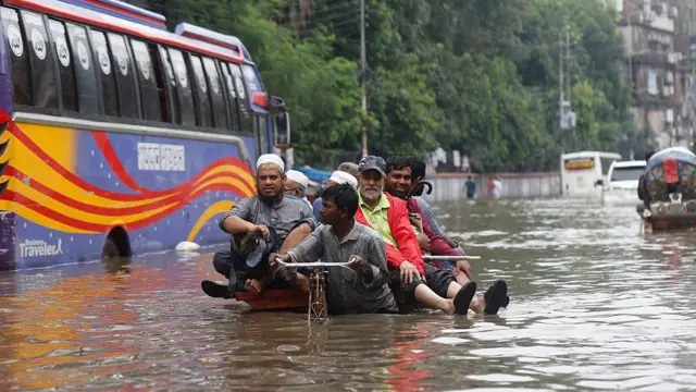 ঢাকার একটি জলাবদ্ধ সড়ক দিয়ে রিকশা টানছেন চালকেরা