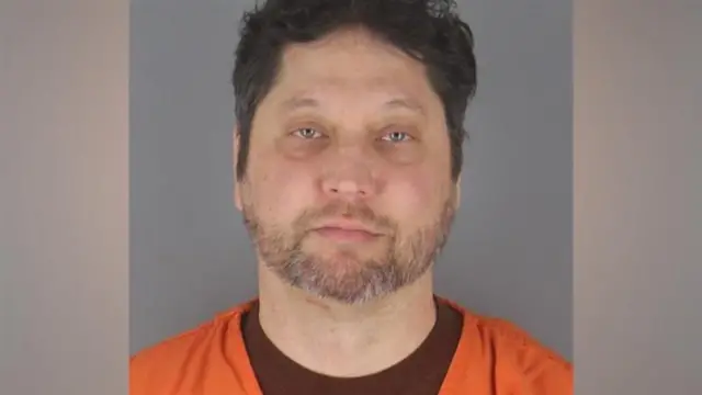 Processing image of Kazmierczak, looking into the camera and wearing an orange shirt