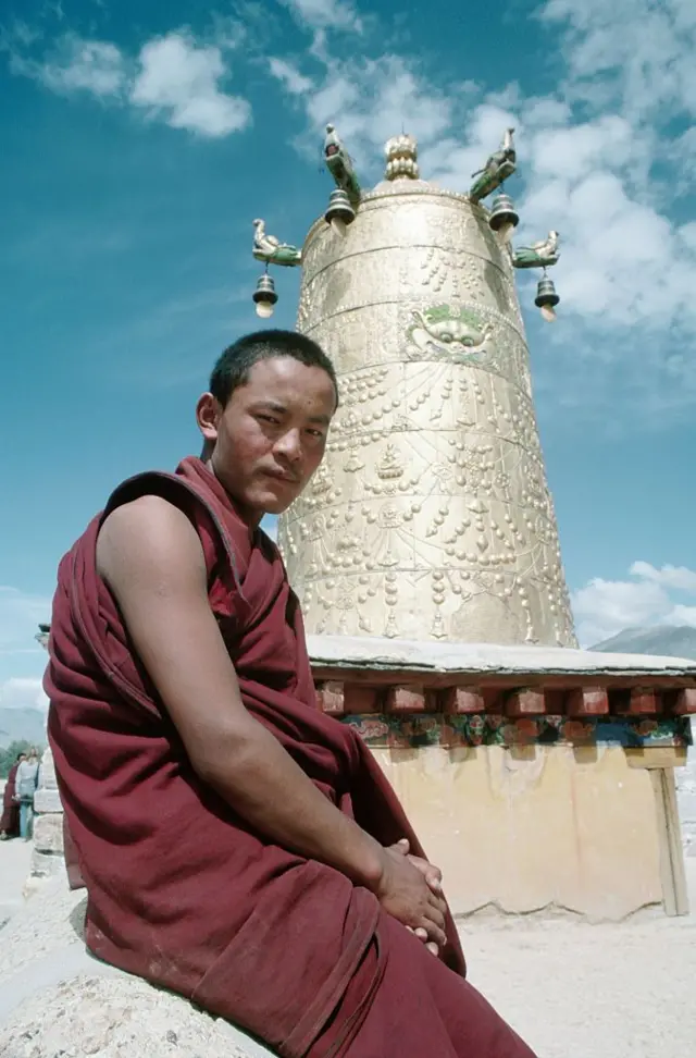 راهب بوذي أمام جرس نحاسي ضخم مزخرف بشكل معقد في معبد جوخانغ، أقدس موقع في التبت