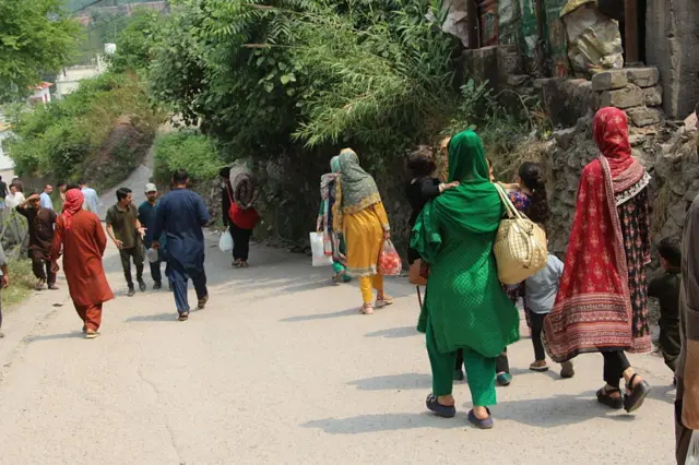 Pakistan idaresindeki Keşmir'de bulunan Muzaffarabad'da siviller çantalarla yürüyor