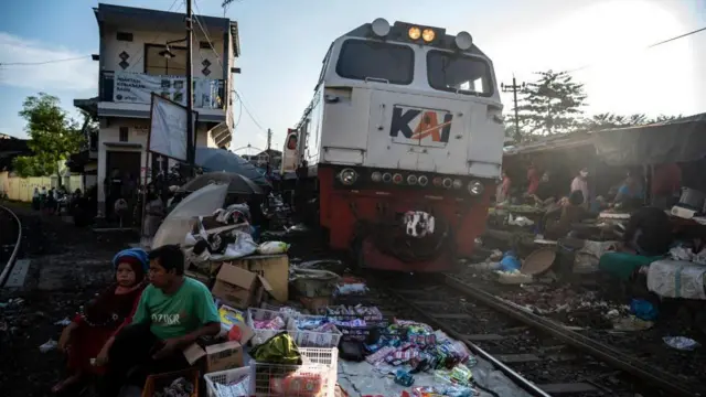 Foto yang diambil pada 8 Juni 2022 ini memperlihatkan pedagang yang berjualan barang di sepanjang rel kereta api Kota Surabaya.